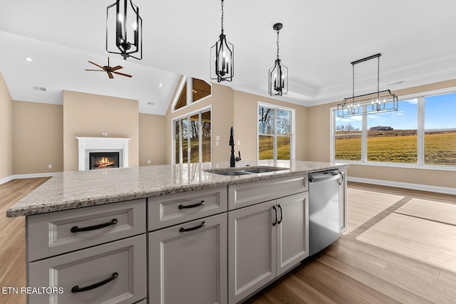 kitchen with stainless steel dishwasher, sink, hanging light fixtures, and gray cabinetry