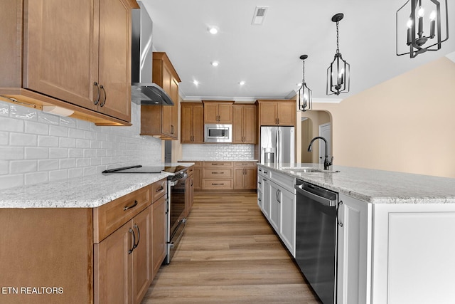 kitchen with white cabinetry, appliances with stainless steel finishes, pendant lighting, light stone countertops, and wall chimney range hood