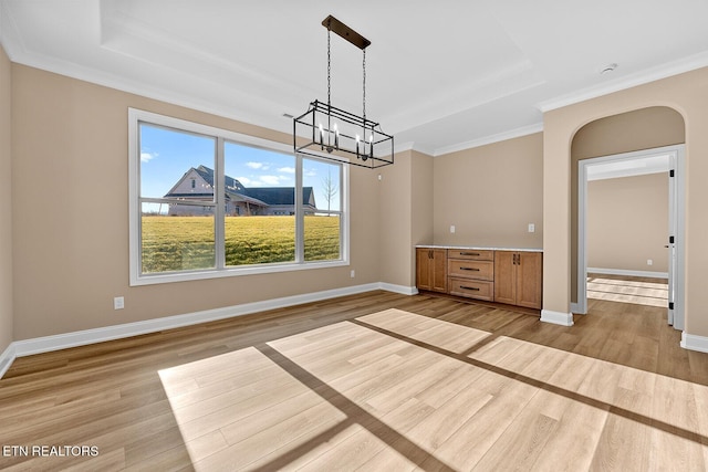 unfurnished dining area with a tray ceiling, light hardwood / wood-style flooring, and ornamental molding