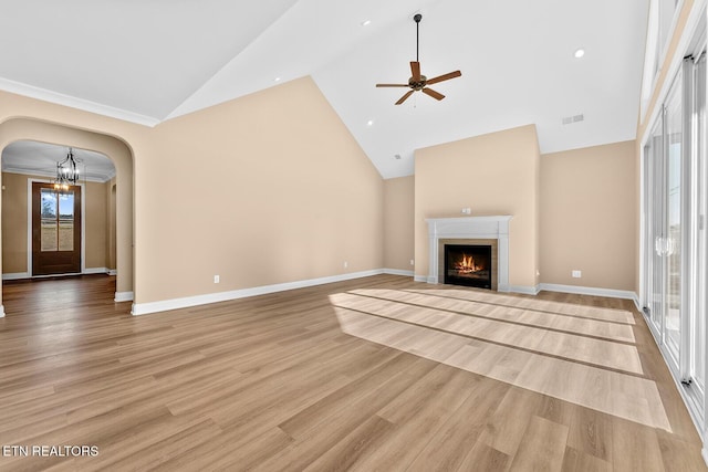 unfurnished living room featuring ceiling fan with notable chandelier, light hardwood / wood-style flooring, and high vaulted ceiling