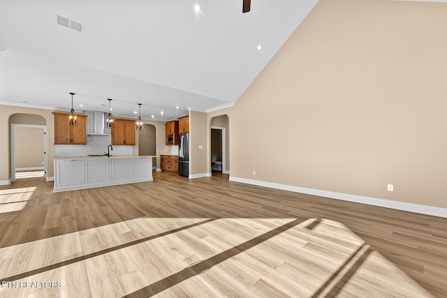 unfurnished living room with high vaulted ceiling, ornamental molding, sink, and light hardwood / wood-style floors