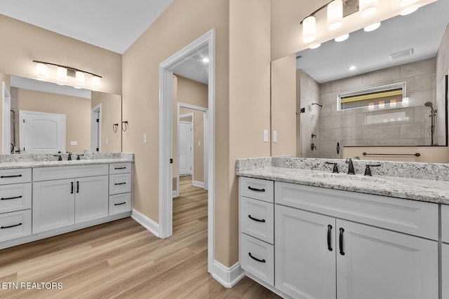 bathroom featuring tiled shower, wood-type flooring, and vanity