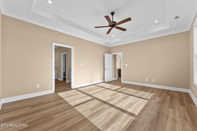 unfurnished bedroom with a raised ceiling, crown molding, and light hardwood / wood-style flooring