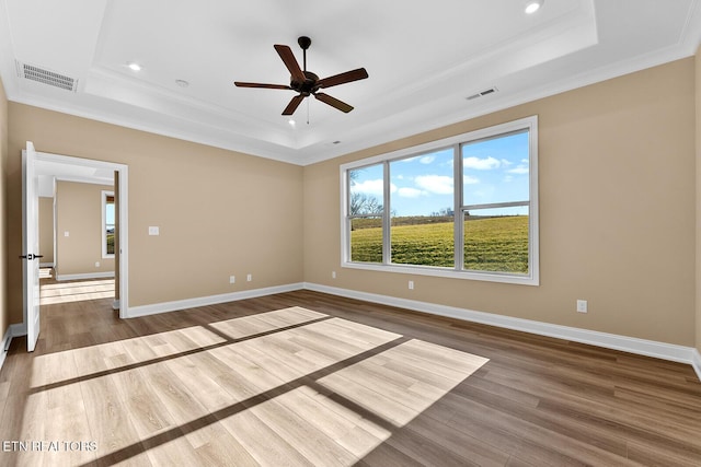 unfurnished room with ornamental molding, hardwood / wood-style floors, ceiling fan, and a tray ceiling