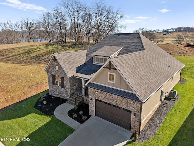 craftsman-style house with a garage, central AC unit, and a front lawn