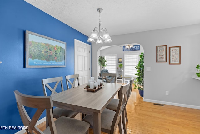 dining space featuring an inviting chandelier, light hardwood / wood-style flooring, and a textured ceiling