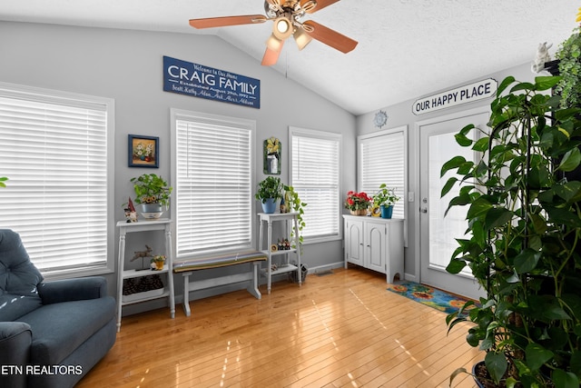 sitting room with vaulted ceiling, ceiling fan, light hardwood / wood-style floors, and a textured ceiling