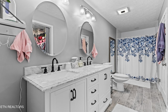 bathroom with vanity, a textured ceiling, toilet, and a shower with shower curtain