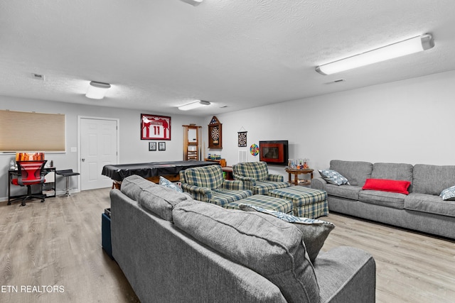 living room featuring billiards, a textured ceiling, and light hardwood / wood-style flooring