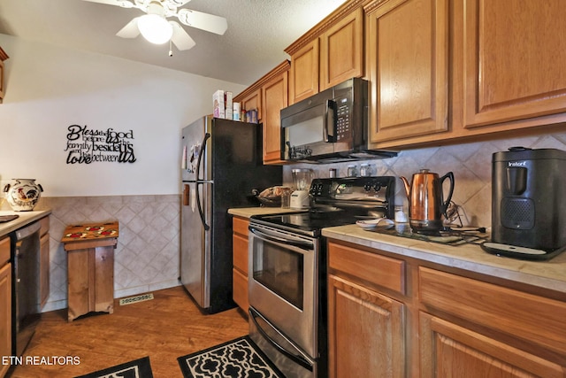 kitchen featuring appliances with stainless steel finishes, tile walls, ceiling fan, light hardwood / wood-style floors, and a textured ceiling