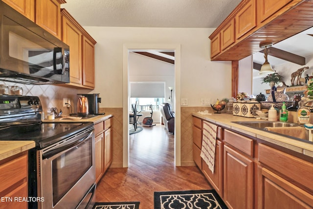 kitchen with stainless steel electric range, sink, tile walls, a textured ceiling, and light hardwood / wood-style flooring