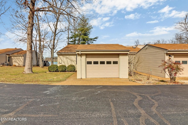 view of front of home featuring a garage, an outdoor structure, and a front lawn