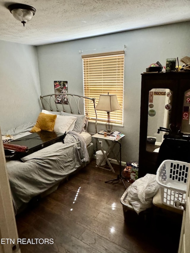 bedroom with a textured ceiling and wood finished floors