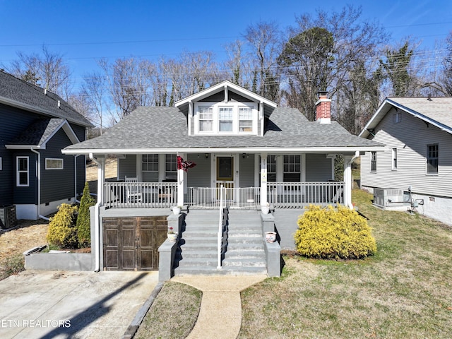 bungalow-style house with central AC unit, a garage, a front lawn, and covered porch