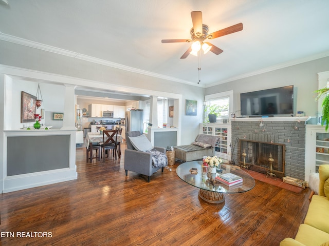 living room featuring ceiling fan, ornamental molding, dark hardwood / wood-style floors, and a brick fireplace