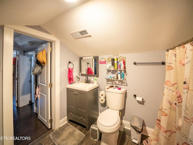 bathroom with lofted ceiling, vanity, wood-type flooring, a textured ceiling, and toilet