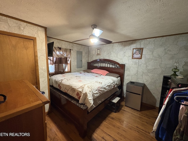 bedroom featuring hardwood / wood-style flooring, crown molding, fridge, and a textured ceiling