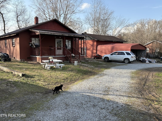 view of front of home with a porch, a carport, and a front lawn