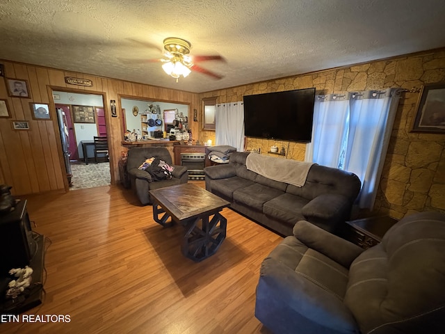 living room with ceiling fan, a textured ceiling, and light wood-type flooring