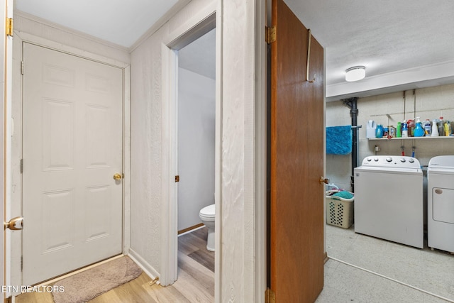 washroom featuring washer and clothes dryer, a textured ceiling, and light wood-type flooring