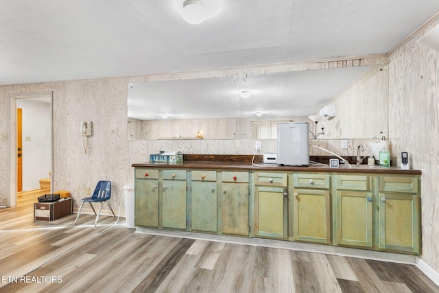 kitchen featuring sink, green cabinetry, and light wood-type flooring