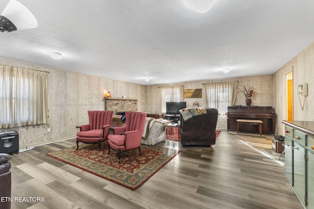 living room featuring hardwood / wood-style floors, a brick fireplace, and a textured ceiling