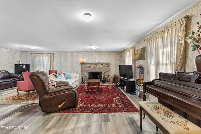 living room with a brick fireplace, hardwood / wood-style flooring, and a wealth of natural light