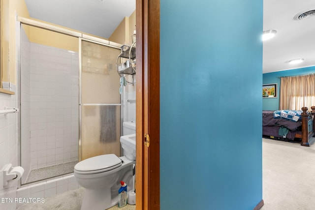 bathroom with tile patterned floors, toilet, and a shower with door