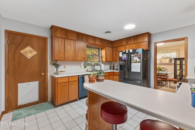 kitchen with light tile patterned flooring, stainless steel appliances, a kitchen bar, and kitchen peninsula