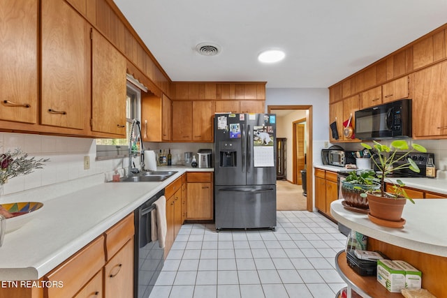 kitchen with tasteful backsplash, light tile patterned floors, and black appliances