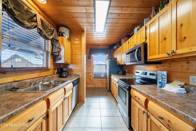 kitchen with sink, stainless steel appliances, light tile patterned flooring, wooden ceiling, and wood walls