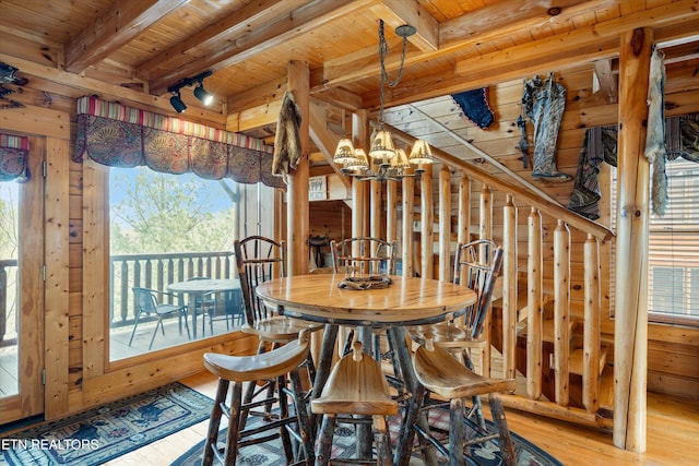 dining space with light hardwood / wood-style flooring, wooden ceiling, wooden walls, and beamed ceiling