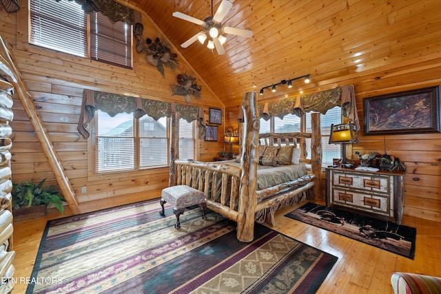 bedroom with multiple windows, wood-type flooring, wooden ceiling, and wooden walls