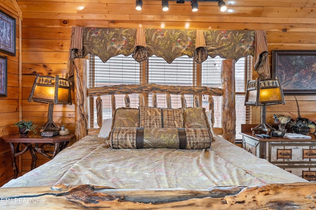 bedroom featuring rail lighting and wood walls