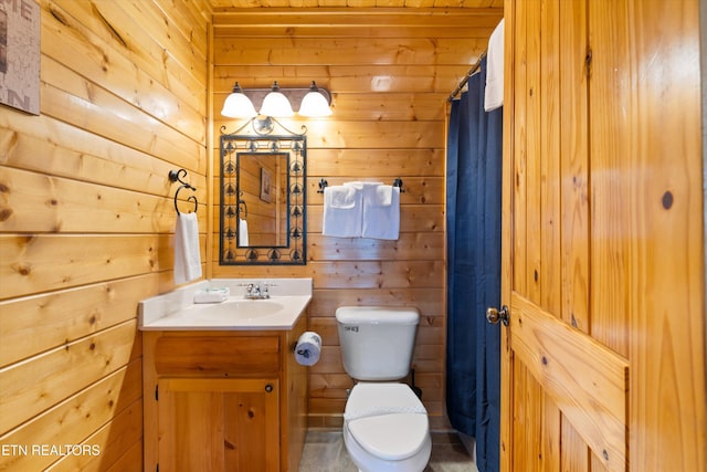 bathroom with vanity, wooden walls, toilet, and walk in shower