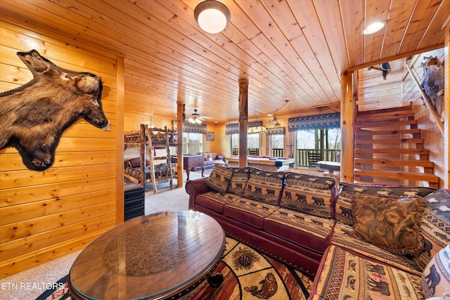 living room featuring ceiling fan, carpet, wooden ceiling, and wooden walls