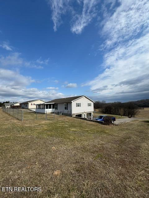 back of property featuring a rural view and a lawn