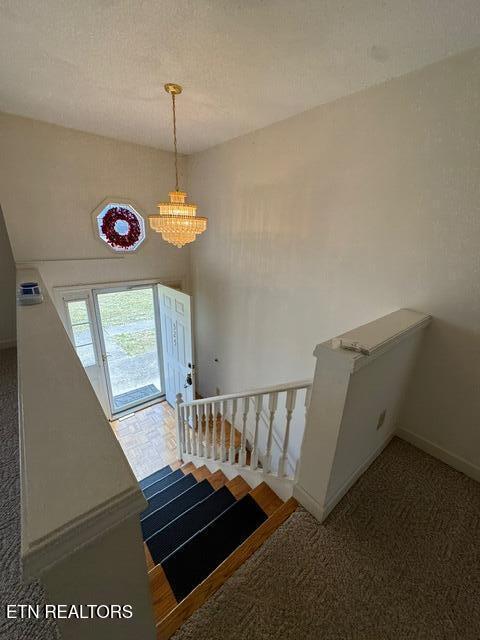 staircase with a notable chandelier