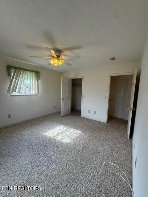 unfurnished bedroom with ceiling fan, carpet flooring, a textured ceiling, and a closet