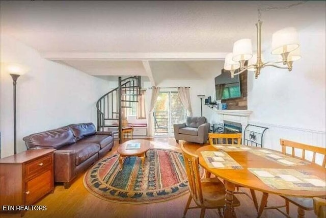 living room featuring beamed ceiling, wood-type flooring, and a notable chandelier