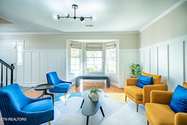 living area with ornamental molding, a chandelier, and light hardwood / wood-style flooring