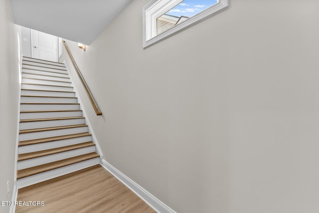 staircase featuring baseboards and wood finished floors