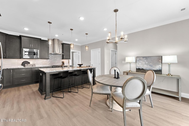 dining room featuring ornamental molding, recessed lighting, light wood-style flooring, and baseboards