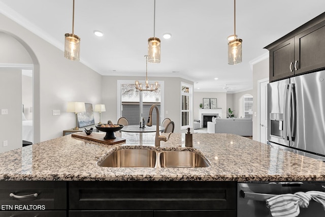 kitchen with appliances with stainless steel finishes, light stone counters, and an island with sink