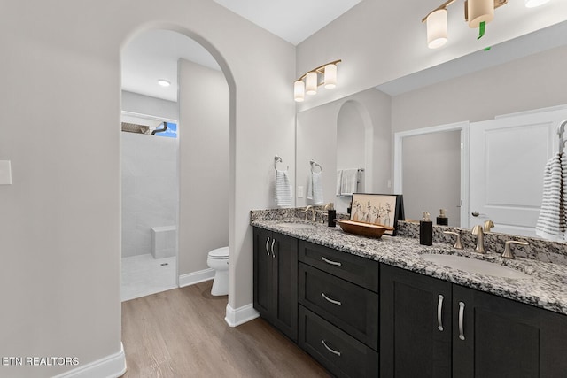 bathroom with wood finished floors, double vanity, a sink, and walk in shower