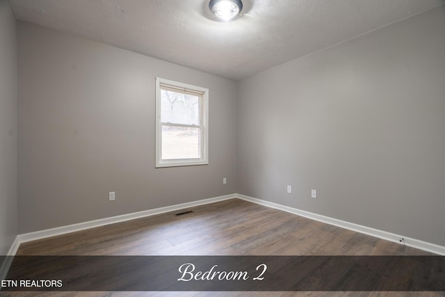 unfurnished room featuring wood-type flooring and a textured ceiling