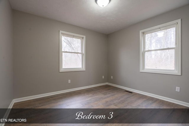 empty room featuring wood-type flooring and a textured ceiling