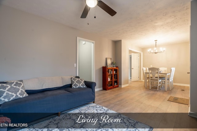 living room with ceiling fan with notable chandelier and hardwood / wood-style floors