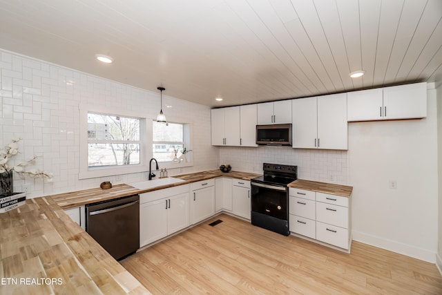 kitchen featuring sink, wooden counters, white cabinetry, black appliances, and decorative light fixtures