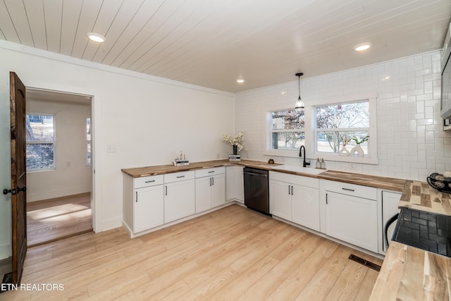 kitchen with dishwasher, white cabinetry, hanging light fixtures, and butcher block counters